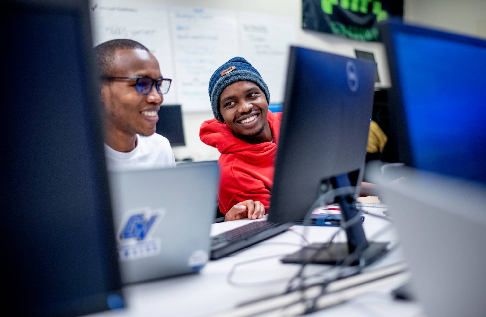 Two students smiling while working at a computer